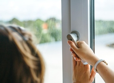 Vrouw opent raam om te ventileren