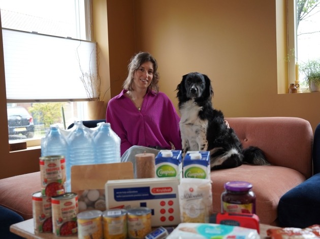 Nienke met haar hond op de bank en het noodpakket uitgestald op de salontafel